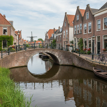 Knik in gracht met lage bakstenen brug